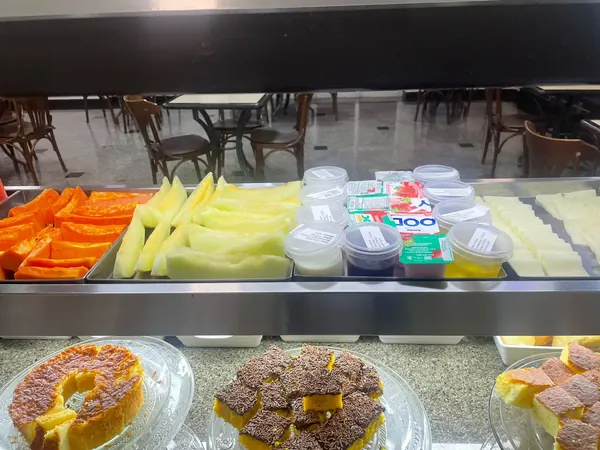 Frutas cortadas, bolos e iogurtes na vitrine do café da manhã