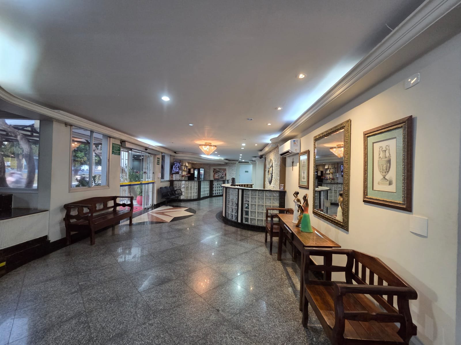 Hall do Hotel Apollo, com bancos e quadros ao longo do corredor