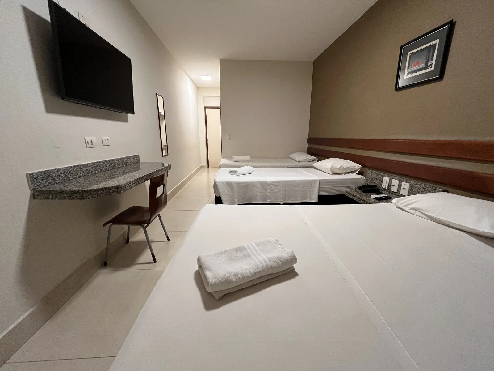 Apartamento quádruplo do Hotel Apollo, com televisão e bancada de apoio