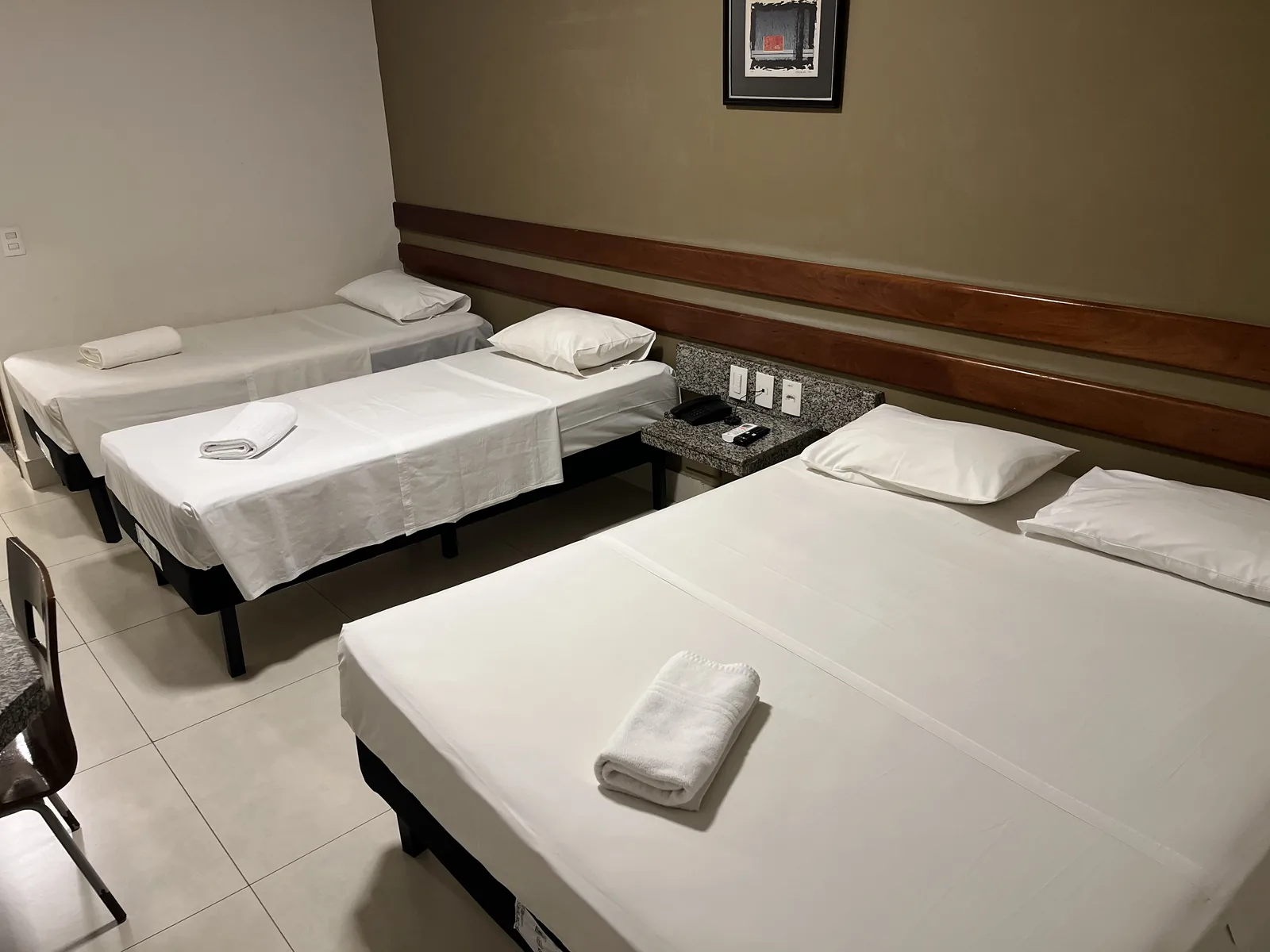 Canto do apartamento quádruplo, com cadeira e as camas de solteiro