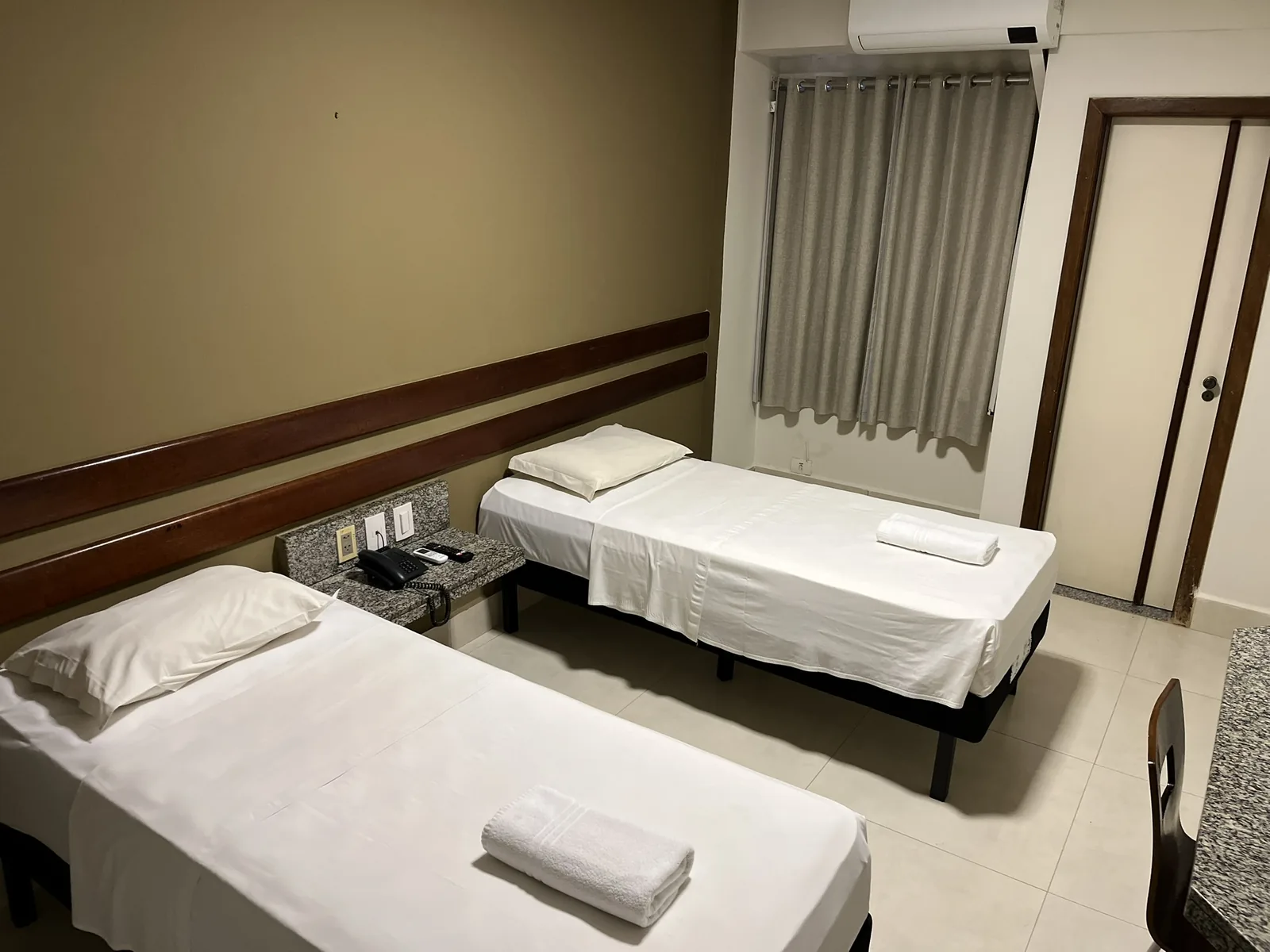 Cama de solteiro do apartamento duplo junto à janela com cortina